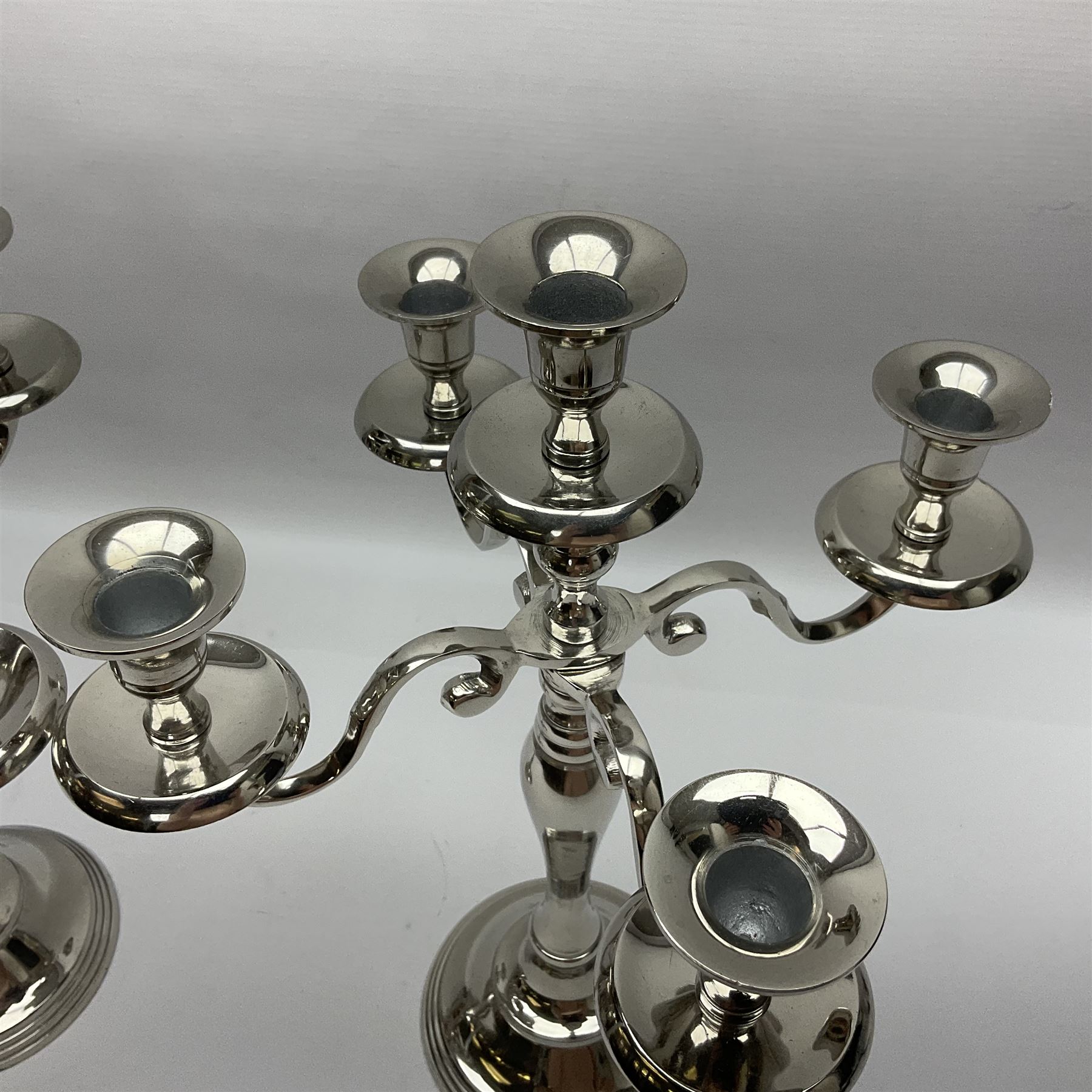Pair of four branch candelabras, urn-shaped nozzles raised upon scroll branches supported from tapering central stem, with a stepped circular base, H40cm