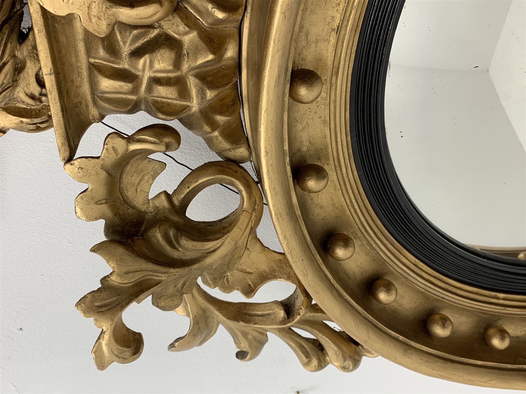 Large Regency carved wood and gesso circular convex mirror, eagle pediment on platform flanked by acanthus leaf scrolls, moulded surround and ebonised slip