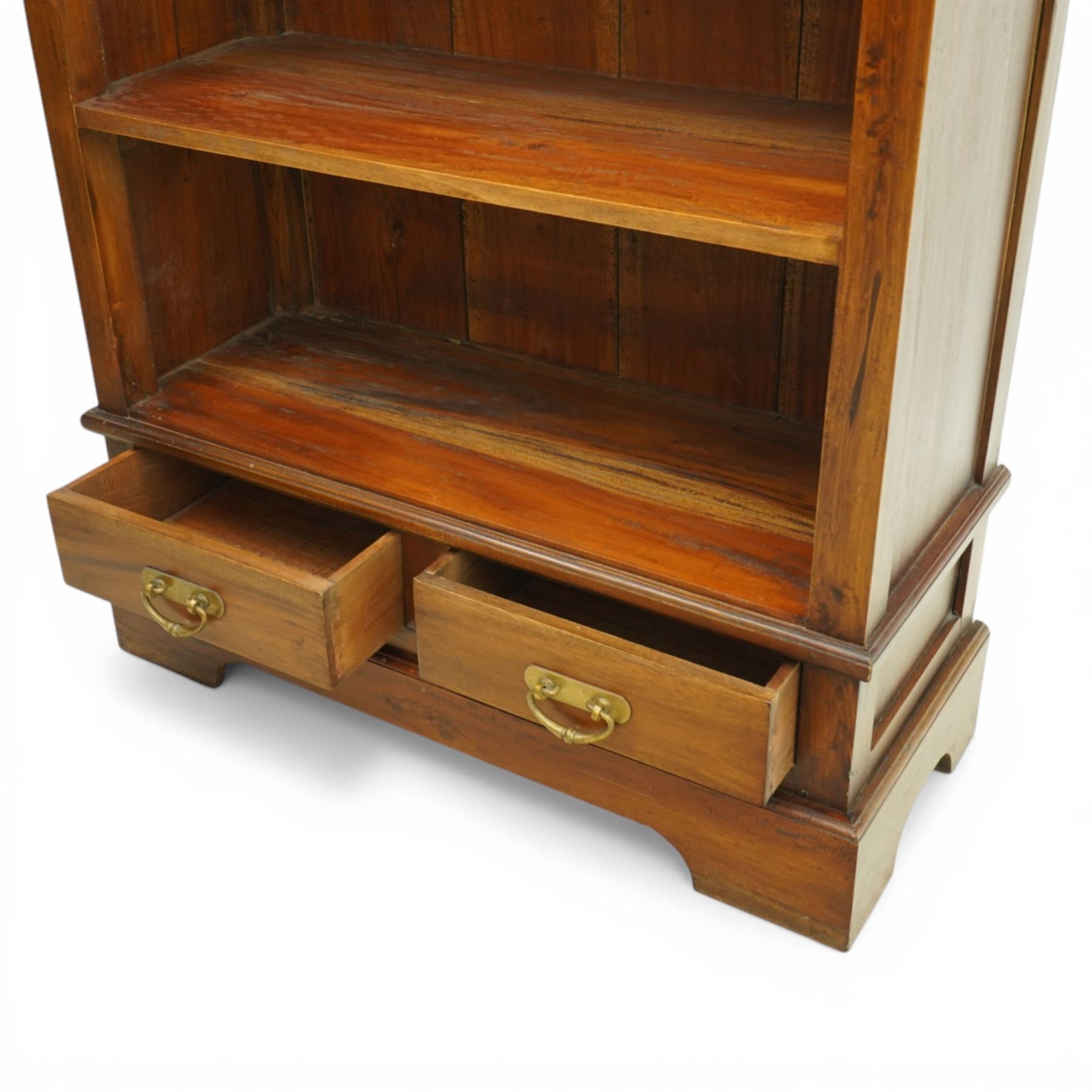 Late 20th century Georgian design hardwood open bookcase, moulded cornice above a shaped frieze, open shelved interior with boarded back, the base fitted with two short drawers with brass swan neck handles, on a shaped plinth
