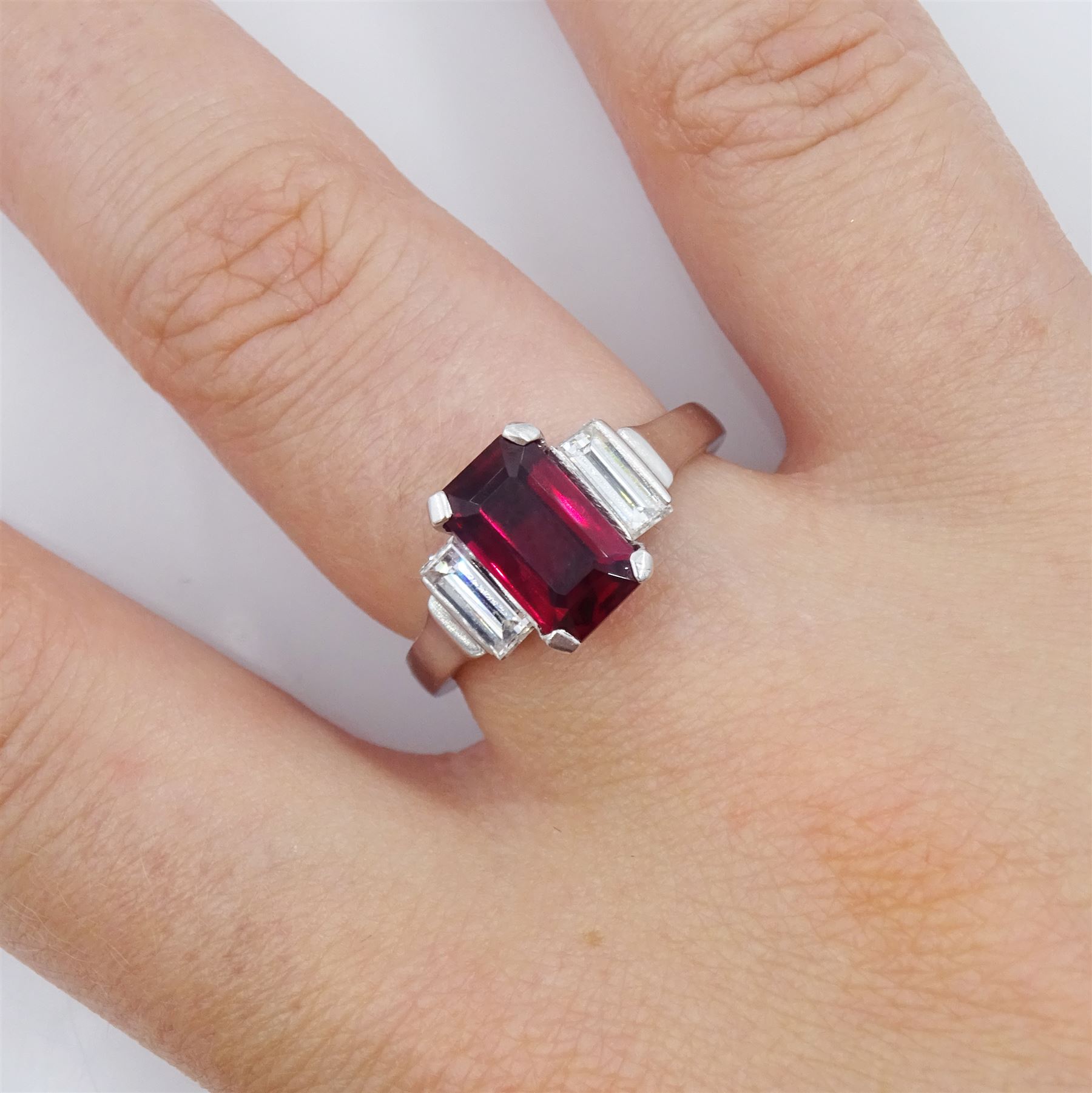 18ct white gold ruby and diamond three stone ring, single emerald cut Thai ruby of approx 2.00 carat, with a baguette cut diamond set either side, hallmarked, total diamond weight approx 0.60 carat