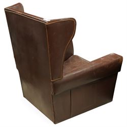 Early to mid 20th century pair of wingback armchairs, upholstered throughout in chocolate brown leather, the backs with deep wings, square padded arms with piped seams, loose seat cushions over solid bases