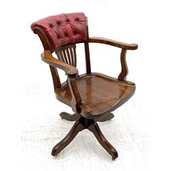 Early 20th century walnut swivel desk elbow chair, deeply button upholstered back in red leather over vase shaped pierced splat, dished saddle type seat, adjustable metal mechanism, on four splayed supports with brass castors
