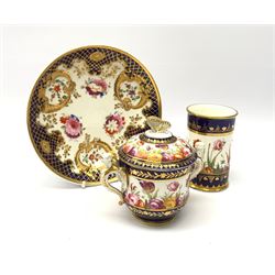 Early 19th century Spode chocolate cup and cover, with twin figural winged handles, decorated with a continuous band of flowers between dark blue gilt detailed borders, H8cm, together with a similarly decorated spill vase, H10.5cm, and a 19th century Ridgway dish, decorated with flowers and moulded cornucopia within a gilt hatched dark blue border, pattern number verso 2/852, D19cm