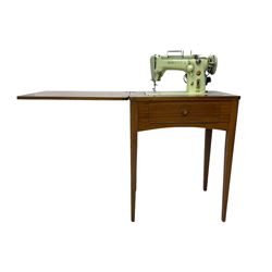 Mid-20th century teak sewing table, rectangular top with hinged fold-out extension revealing built-in Singer sewing machine, fitted with single hinged drawer, on square tapered supports; various Singer accessories to include Fashion Discs and Motor Controller