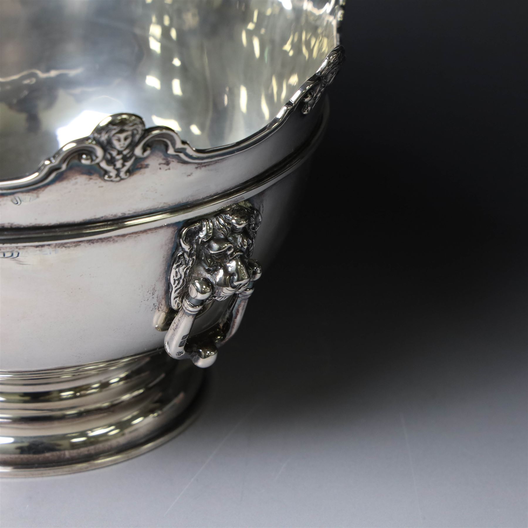Edwardian silver Monteith punch bowl, the scalloped rim with strapwork and figural decoration, with two lion mask mounted ring handles, upon a circular stepped foot, hallmarked London 1903, maker's mark worn and indistinct, H15cm, D23cm