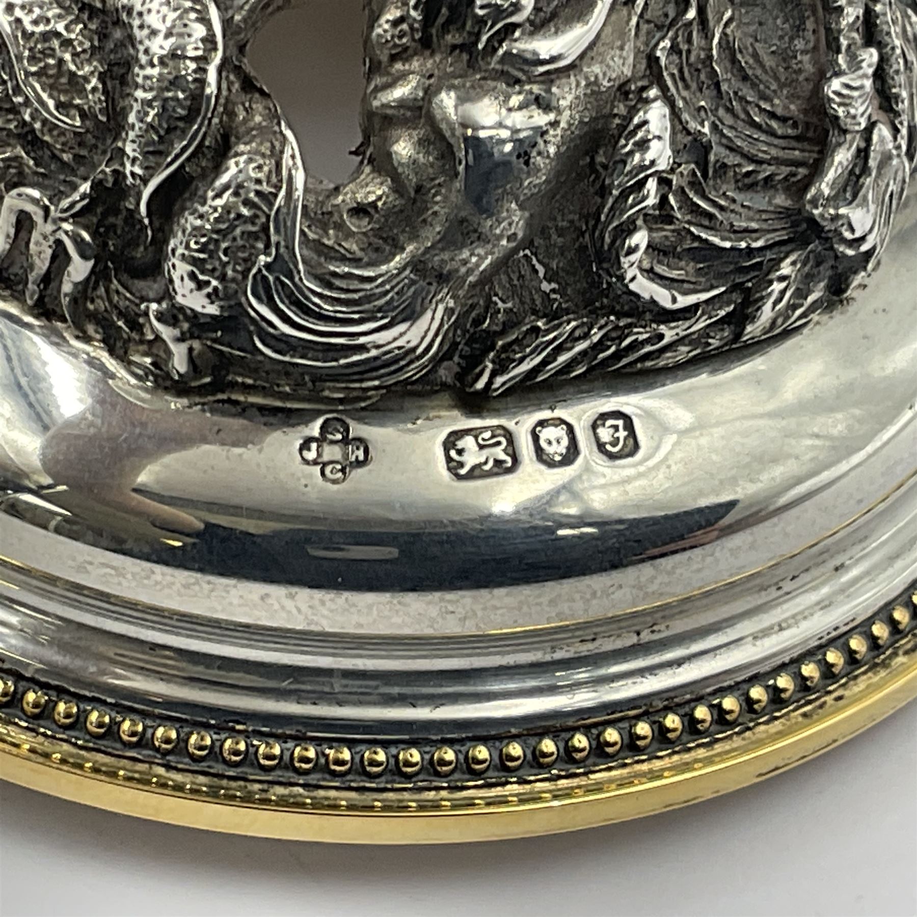 Modern limited edition silver mounted nautilus shell cup, no. 42/150, the pearlescent shell cup with silver-gilt strapwork to rim, upon a stem modelled as a putto supporting a gilt cornucopia and circular domed foot depicting Poseidon amongst swirling waves, hallmarked by St James House Company, London 1980,  H17.5cm