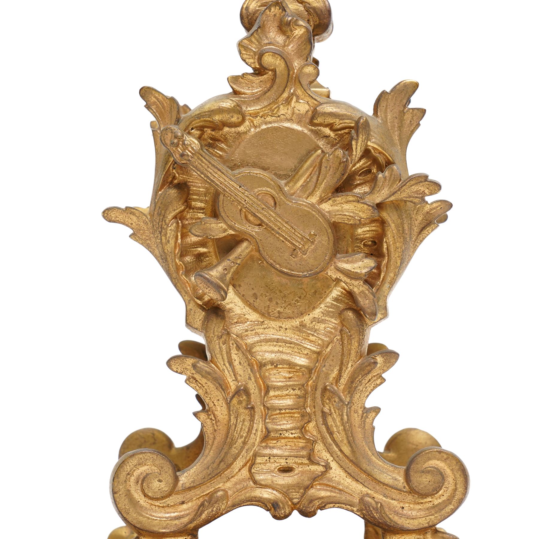 French-Late 19th century 8-day gilt brass rococo style mantel clock, c1890, waisted case  decorated with scroll work, leaves and musical instruments, resting on an attached plinth with splayed feet, dial within a glazed brass bezel with a gilt repoussé centre, porcelain cartouche Roman numerals and steel fleur-di-Lis hands, with a twin train movement, recoil anchor escapement and countwheel strike, sounding the hours and half-hours on a bell. With a matching pair of five-light candelabra. No Pendulum or Key.