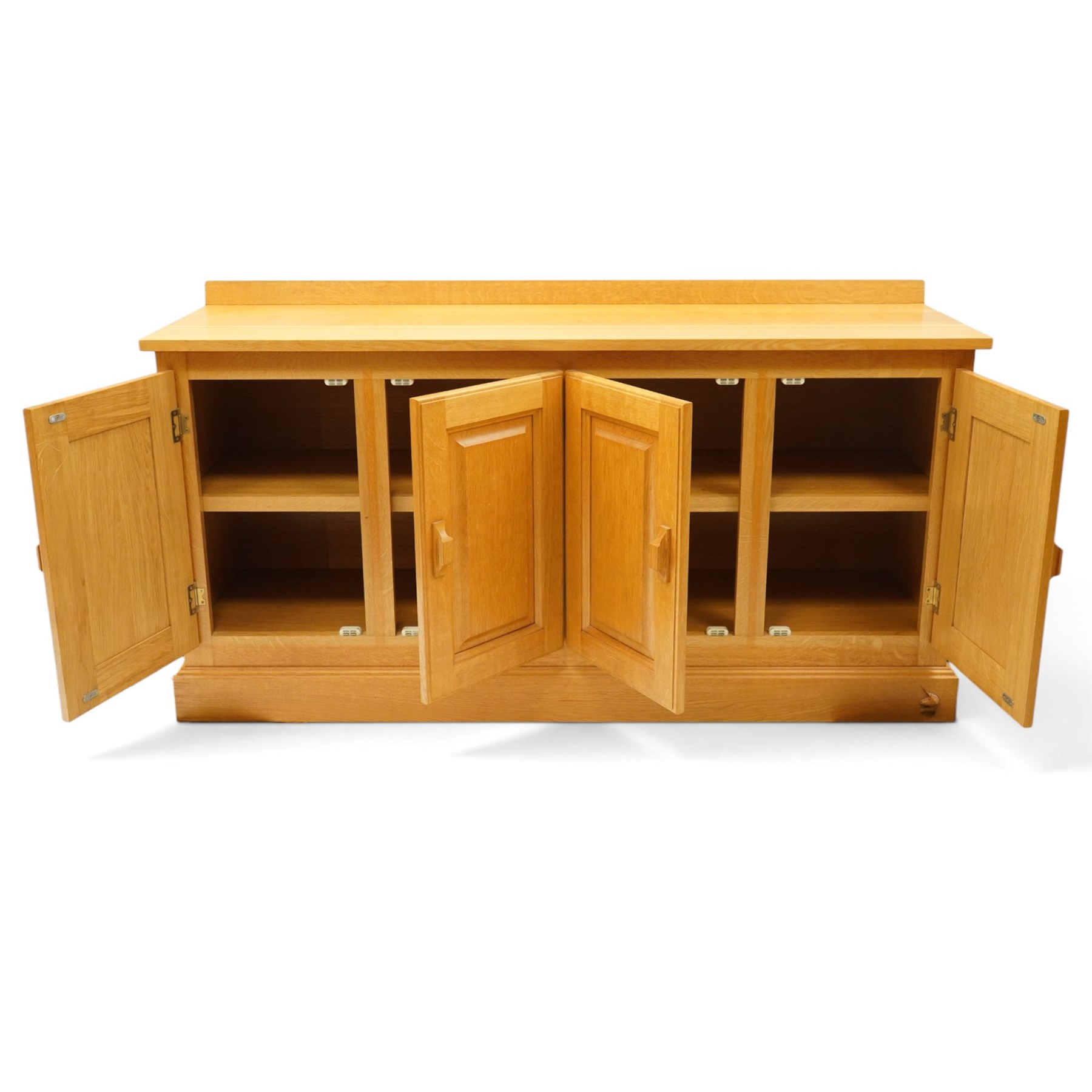 Unicornman - craftsman made oak low-cupboard or sideboard, rectangular top with raised back, fitted with four panelled cupboard doors, on skirted base applied with carved unicorn signature, by Geoff Gell of Coxwold