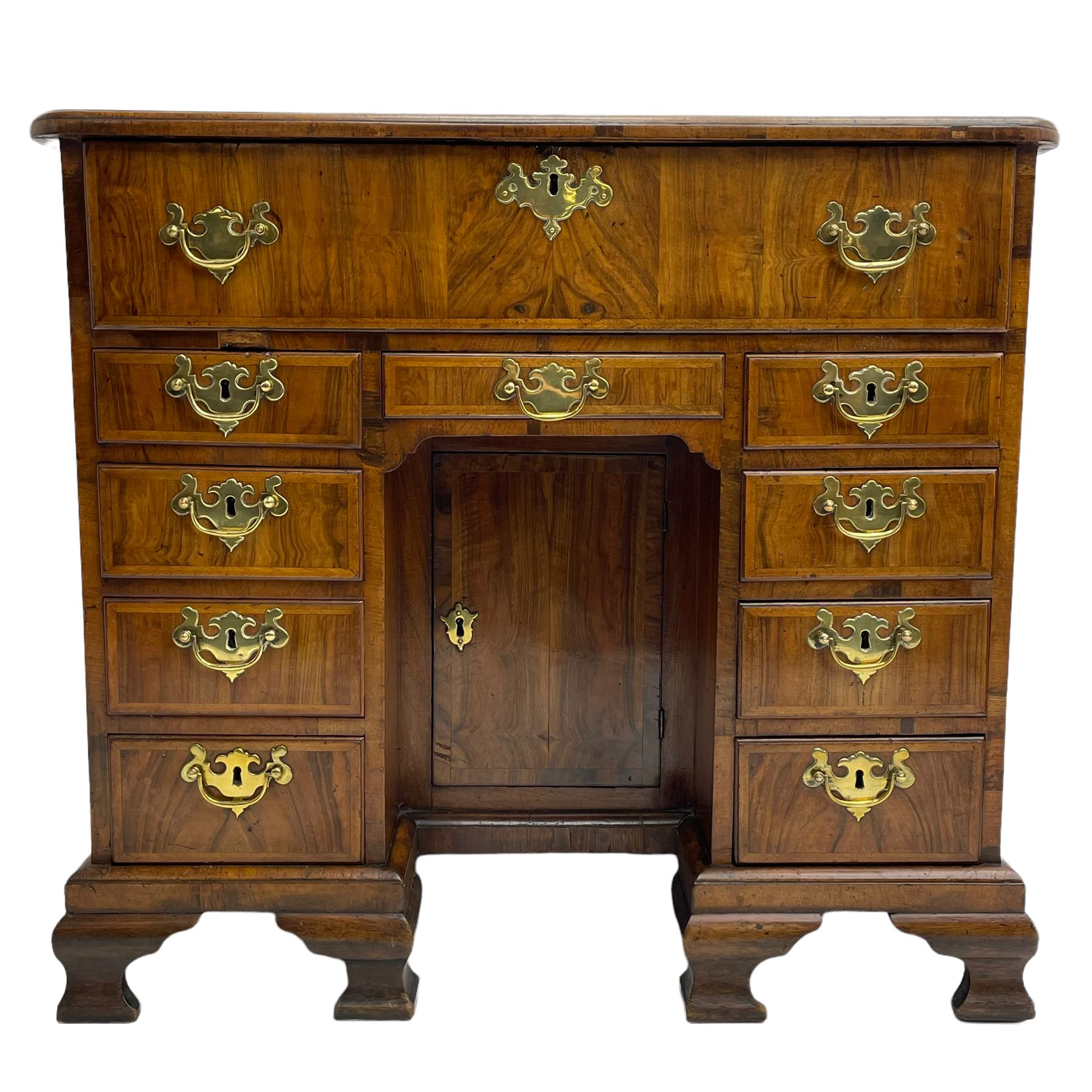 Early 18th century Queen Anne figured walnut kneehole desk with secretaire drawer, moulded and book matched top with walnut band, the top drawer with fall front enclosing small drawers and pigeon holes, fitted with nine drawers and central recessed cupboard, on ogee bracket feet