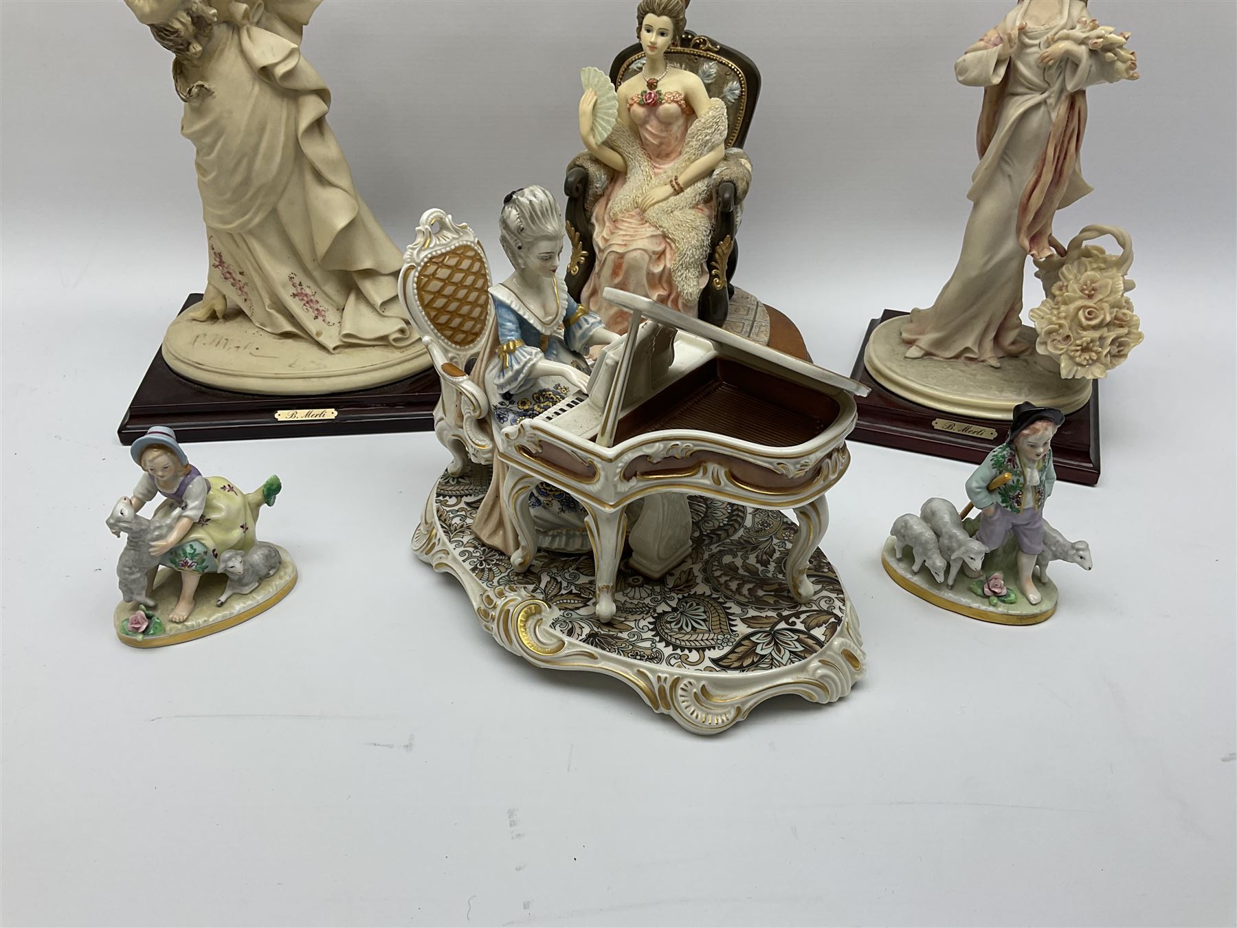 A small pair of Sitzendorf figures modelled as shepherd and shepherdess, H10.5cm together with a Dresden porcelain figure modelled as a female figure playing the piano, H17cm, a Naples figure with floral bouquet, H27.5cm,  a Naples figure holding a dog, H33cm, and a Leonardo Collection figure, Interlude, H24cm. 