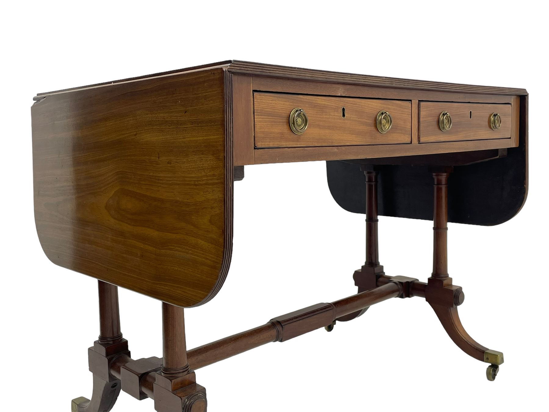 George III mahogany sofa table, rectangular drop-leaf top with reed moulded edge and rounded corners, fitted with two frieze drawers and two opposing false drawers, quadruple collar turned pillar supports on turned and block platforms, splayed and moulded supports with brass cups and castors 