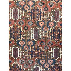 Persian crimson ground rug, the field decorated with three rows of stylised plant medallions and small flowerhead motifs, repeating floral design border with guards 