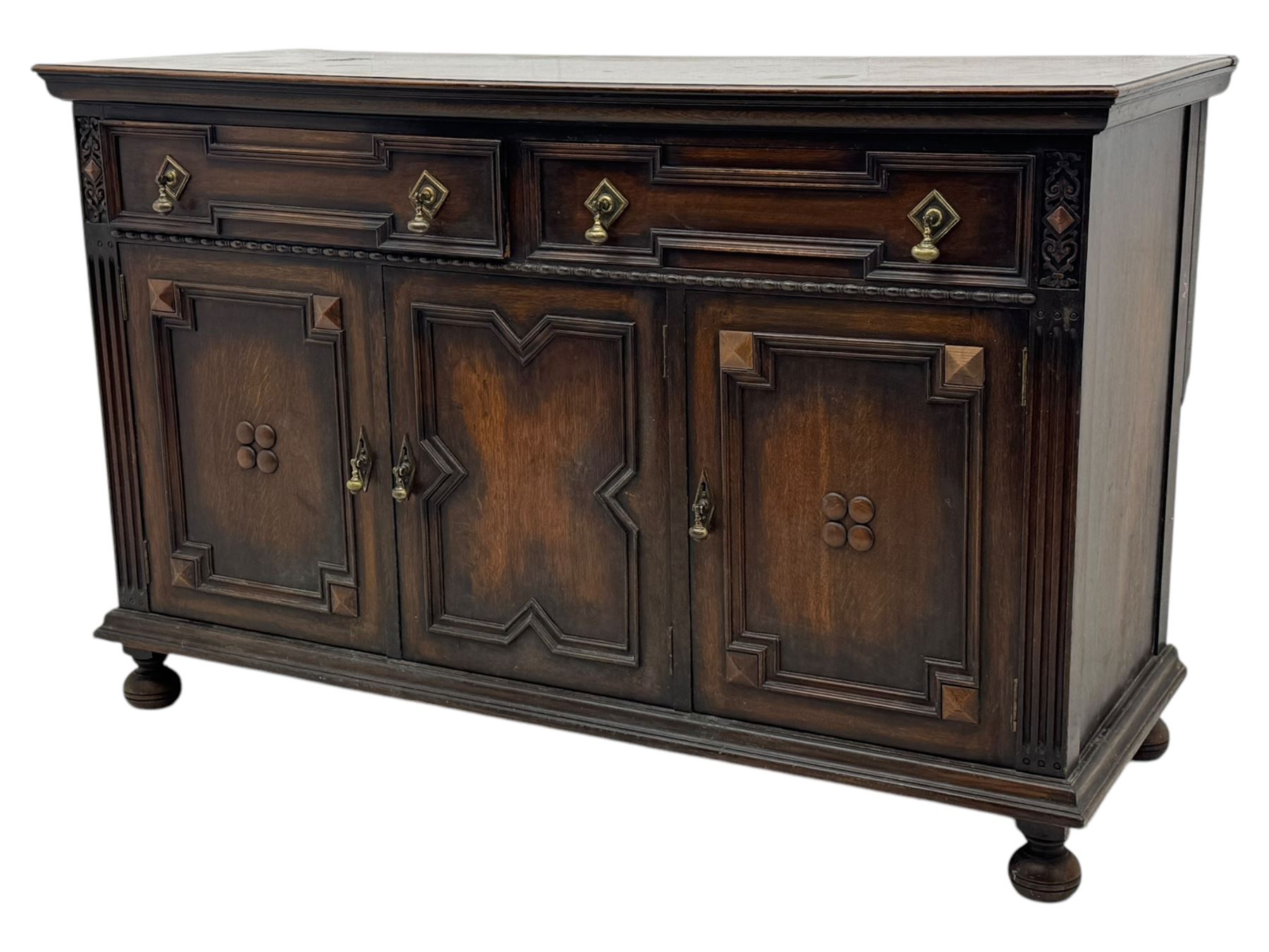 Jacobean-style oak dresser base with two frieze drawers above three cupboards with panelled and moulded decoration, fitted with drop handles, supported on bun feet, circa 1900