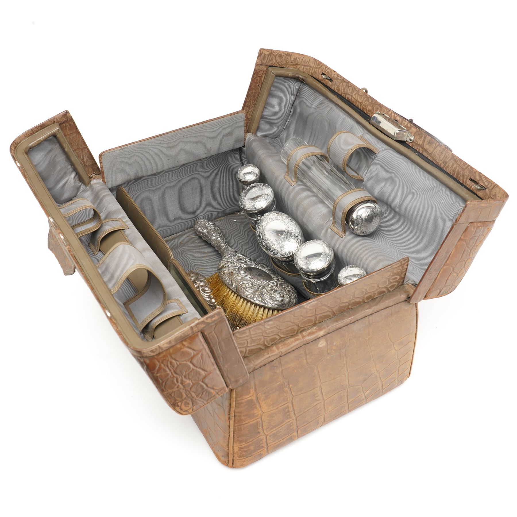 Ladies Edwardian crocodile travelling toilet case with watered silk interior containing six silver mounted glass jars Birmingham 1909 Maker Neal Bros. and a three piece dressing table set Sheffield 1898 W35cm
