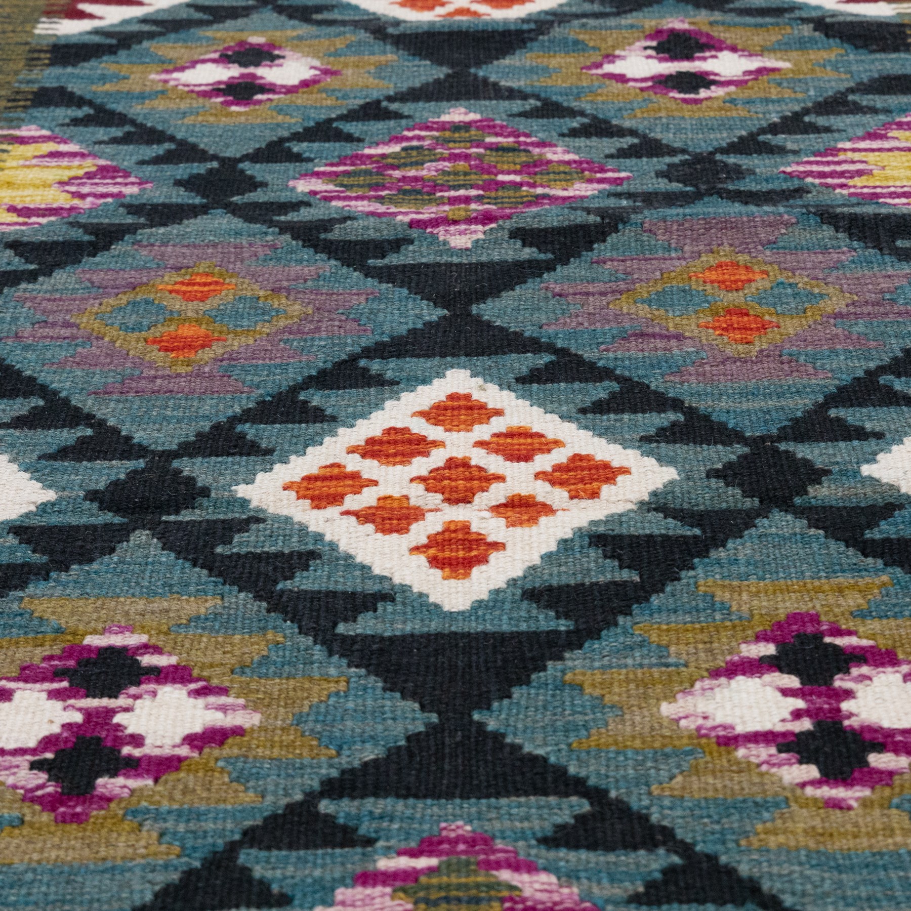 Afghan kilim teal ground runner rug, the field decorated with assorted lozenges with geometric motifs and dark indigo borders, enclosed by a narrow striped guard band