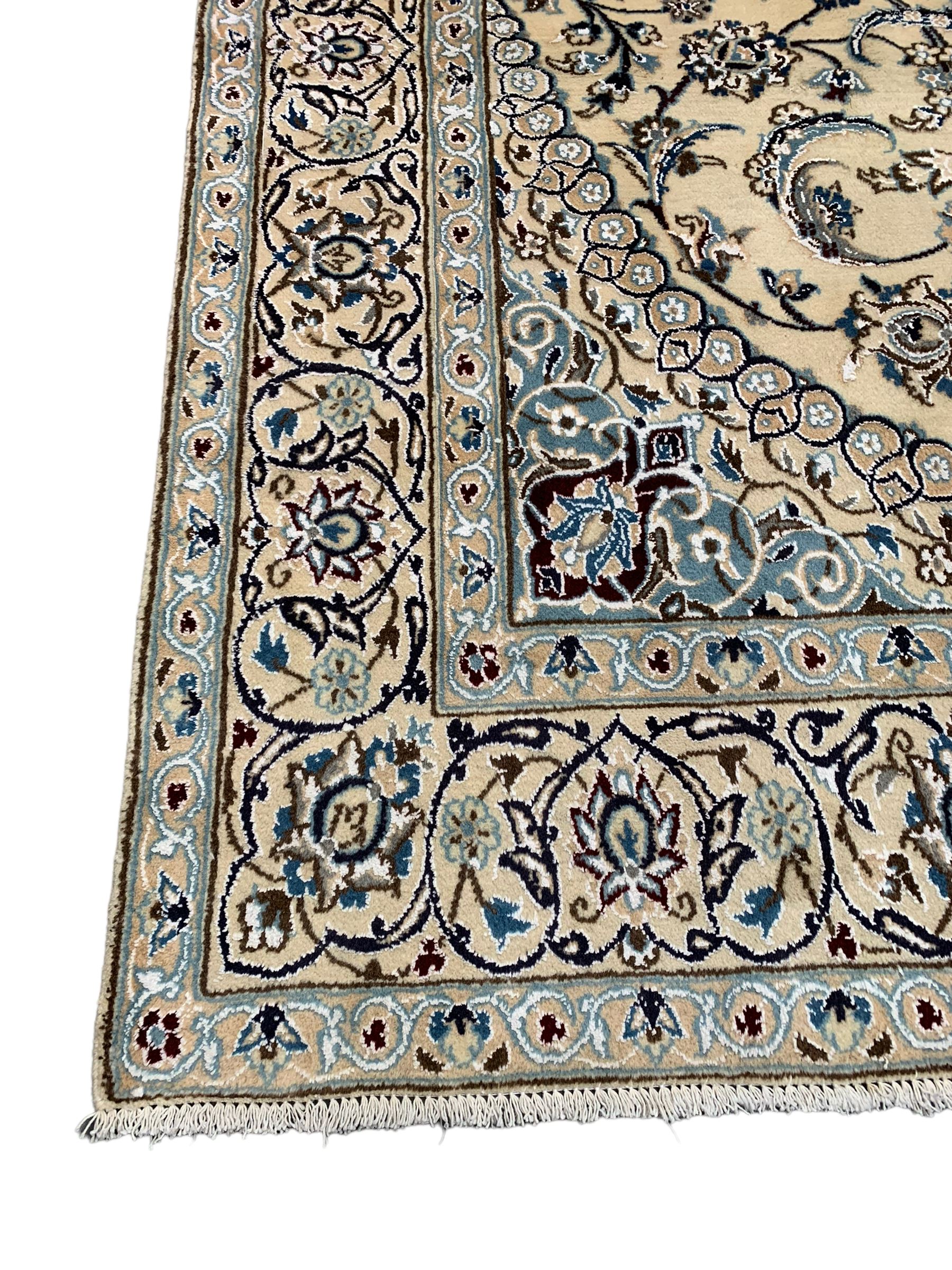 Persian Kashan ivory ground rug, central medallion surrounded by scrolling leafy branches and stylised flowerhead motifs, scrolling border decorated with further stylised plant motifs