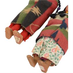 Two Skookum Native American Indian dolls with foot label, with painted composition heads, side glancing eyes, black hair wig, stuffed rigid body, original clothes, the male with feather headdress, the female with baby on back, H32cm
