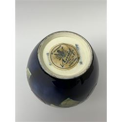 A Moorcroft vase, decorated in the clematis pattern upon a dark blue glazed ground, with paper label beneath detailed Potter to the late Queen Mary, H12.5cm.