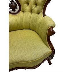 Victorian walnut settee, triple back with pierced and scroll-carved cresting rails over carved fruit and foliage decoration, upholstered in buttoned green fabric, serpentine seat and carved apron, on cabriole feet