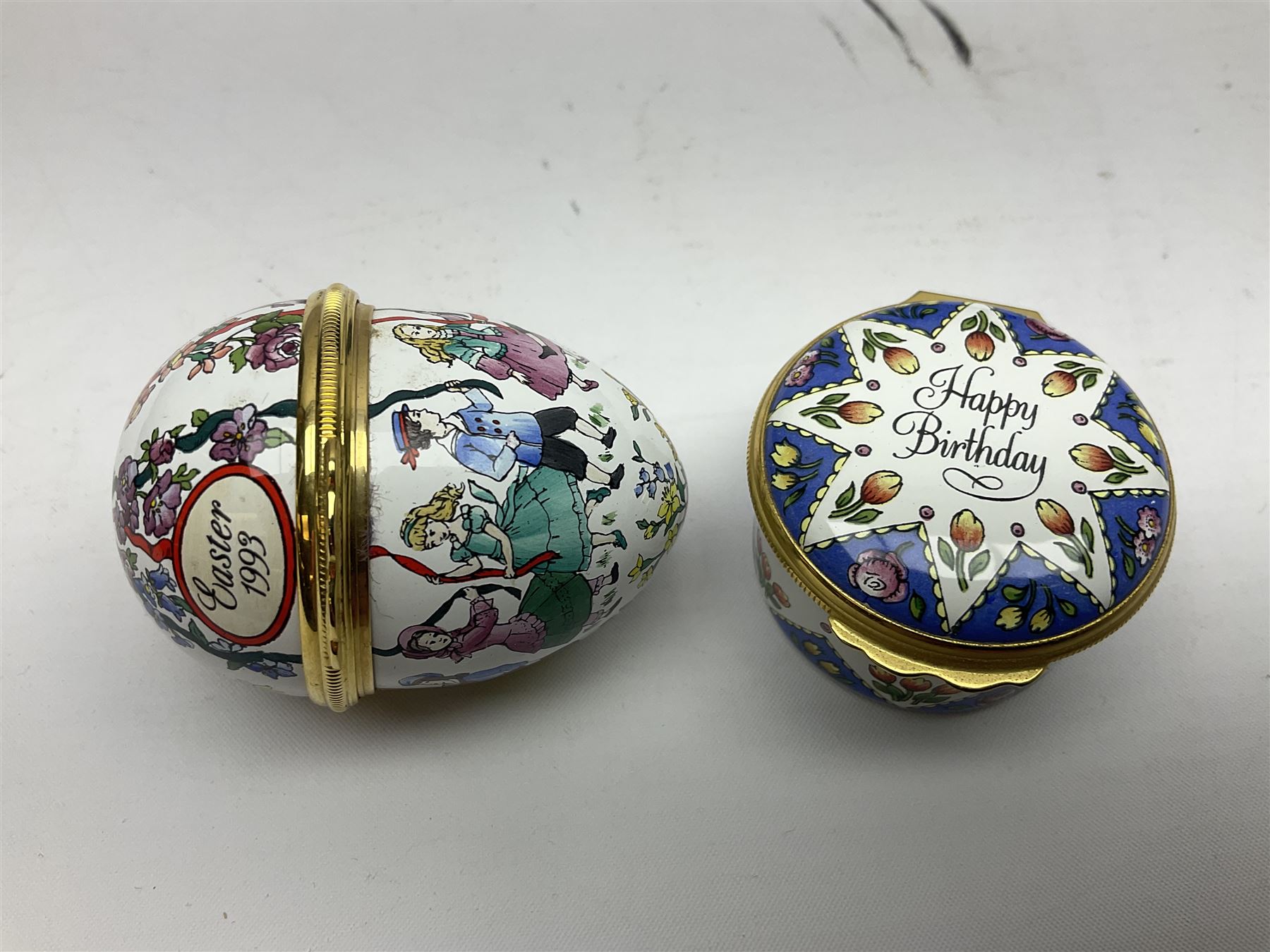 Halcyon Days bonbonniere, modelled as pink roses in a planter painted with a blue and white Japanese scene, together with five Halcyon Days enamel boxes, one a larger example depicting 'The Becket Casket' and four smaller boxes, including The 1993 Easter Egg, Happy Birthday and Statue of Liberty examples, all boxed, Becket Casket D8cm