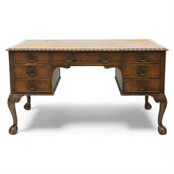 Waring & Gillow - Early 20th century mahogany desk, the leather-inset top above a shaped kneehole, central compartmented frieze drawer flanked by twin banks of of three drawers, each with brass handles, raised on cabriole legs with carved ball and claw feet (Height from floor to underside 62cm)