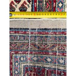 Northwestern Persian Bottehmir hand-knotted rug, ivory field with an all-over design of boteh motifs arranged in diagonal rows within multiple borders and a primary madder red field with stylized vine and flowerhead motifs, 320cm x 214cm 