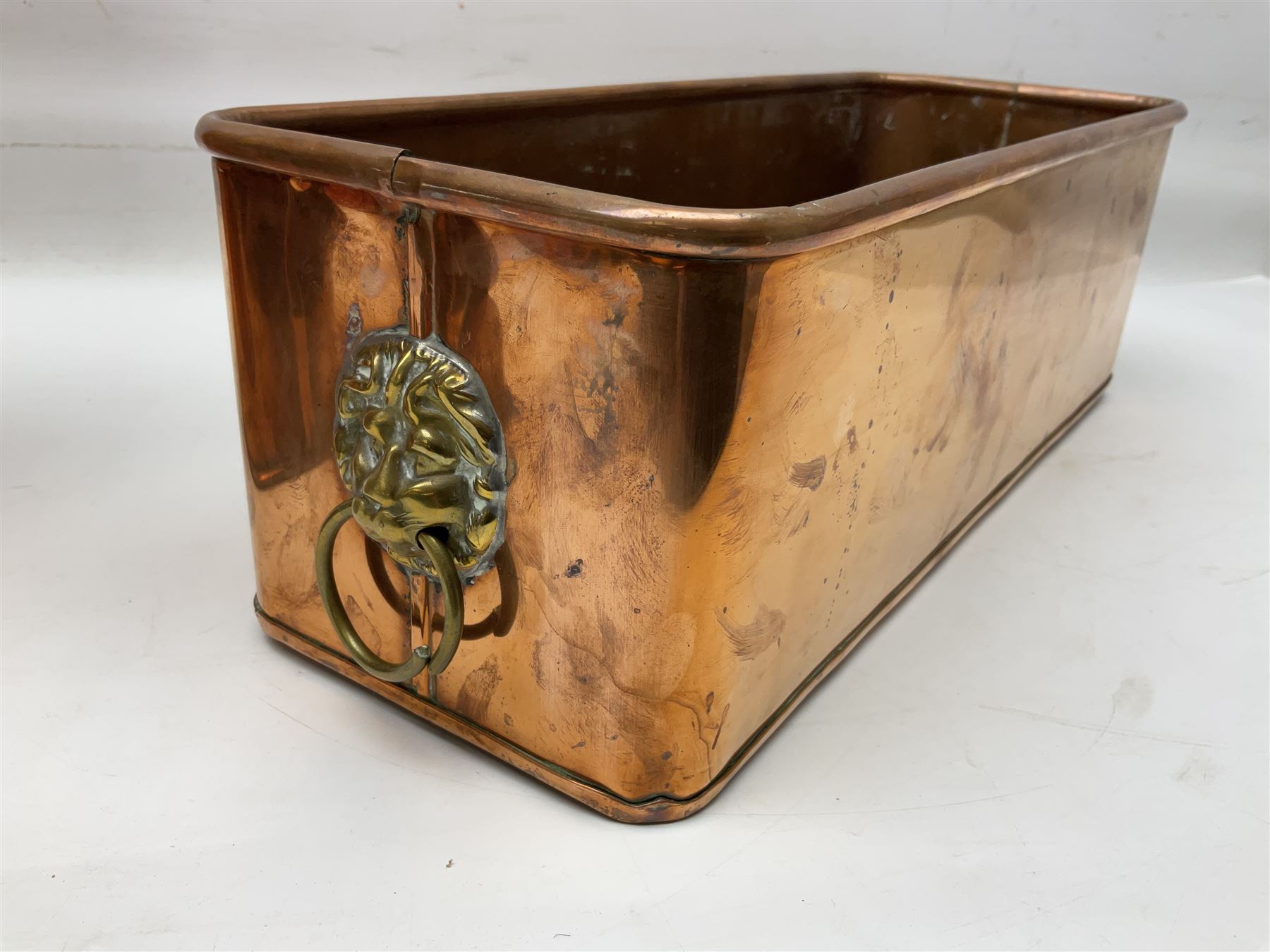 Victorian copper hot water urn, the body of plain cylindrical form with brass tap, the slightly domed lid with brass finial, together with a rectangular copper planter, with twin brass lion mask handles, urn H35cm