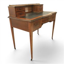 Maple & Co - Edwardian mahogany inlaid writing desk, the superstructure with pierced brass gallery, above an inset mirror and two short drawers, inset leather writing surface, bow fronted with crossbanded drawers and brass swan neck handles, square tapering supports terminating in castors 