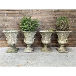 Set of four Victorian design cast stone Grecian urns, tapering form cast with figures and handles, square plinth bases