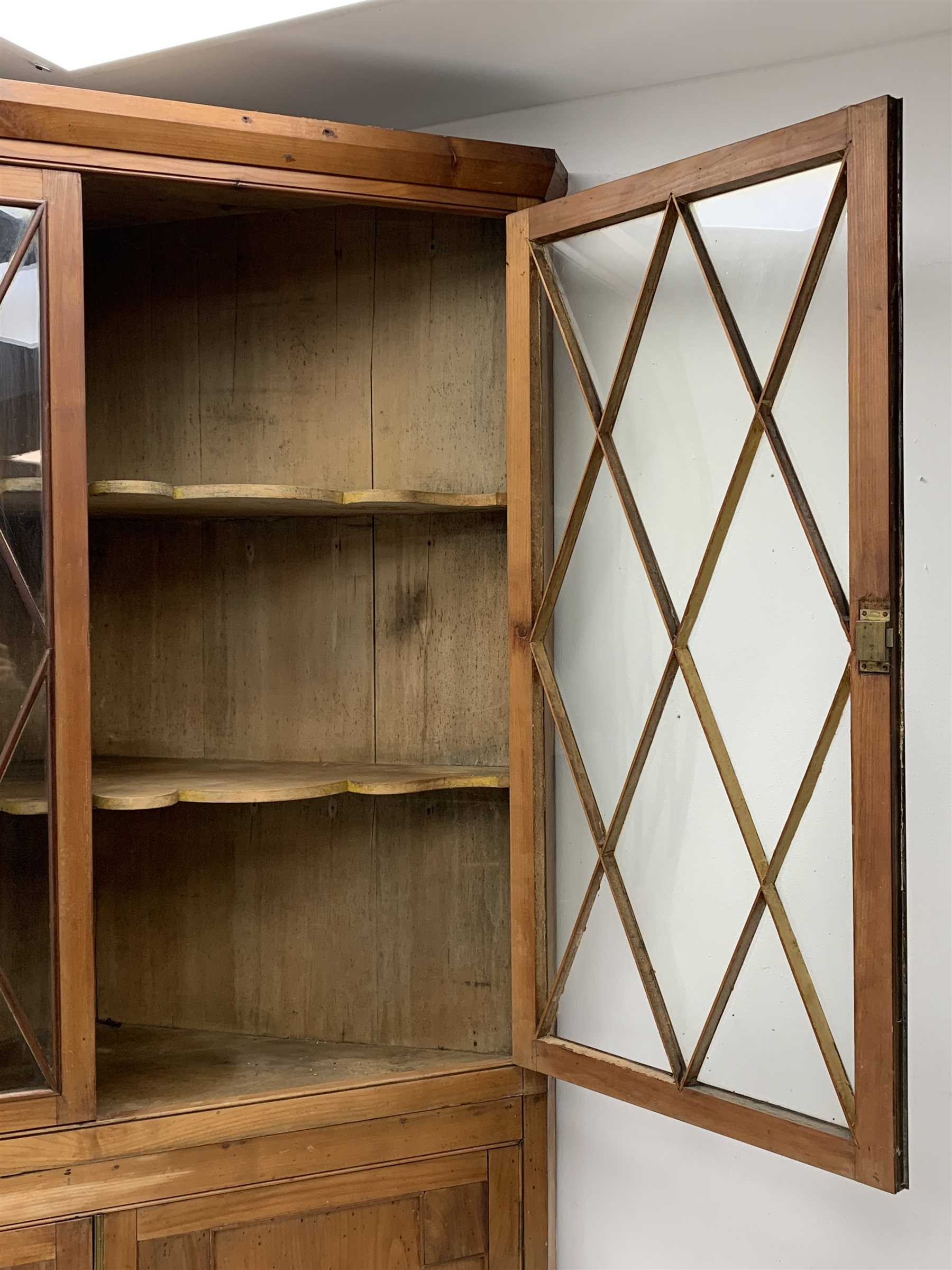 Large late 19th century sycamore corner cabinet, the top section with two astragal glazed doors enclosing two shaped shelves, the lower section enclosed by two panelled doors with square spandrels, W128cm, H215cm