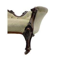 Victorian walnut chaise longue or settee, shaped back carved with cartouche motifs and foliage, upholstered in buttoned pale fabric with sprung seat, scrolled arm terminals on shaped supports with cartouche carved knees, cabriole feet on brass and ceramic castors 