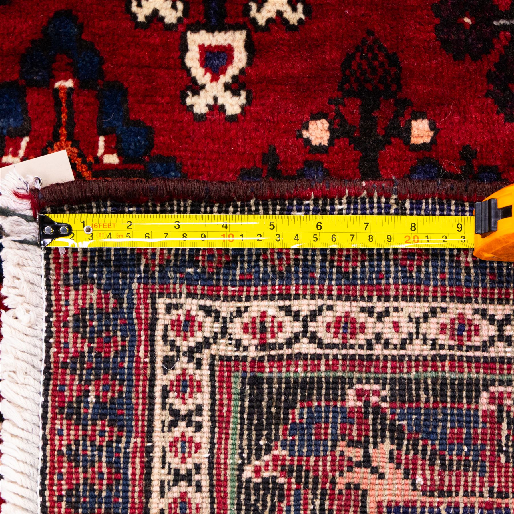 Central Persian Joshagan hand-knotted rug, madder-red field with central stepped lozenge medallion enclosed by angular spandrels, field decorated with repeating stylized geometric floral motifs and small diamond devices enclosed by a dark border of geometric ornament between multiple guard stripes, with cotton fringe ends  