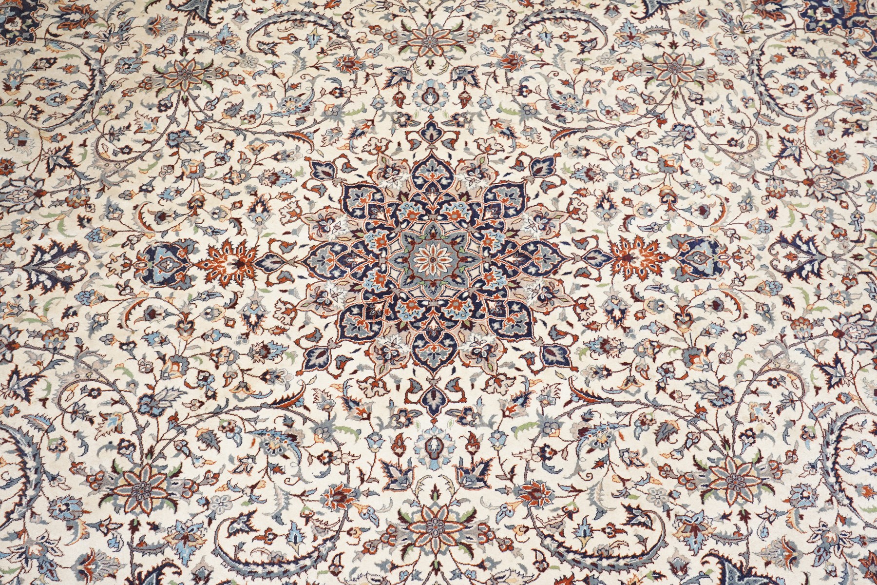 Persian ivory ground Kashan carpet, the busy field decorated with a central floral pole medallion with matching spandrels, the field profusely decorated with scrolling foliate motifs, the crimson guard stripe with repeating scrolling palmettes