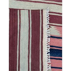 Kilim muted pink ground runner, decorated with rows of horizontal bands in muted tones, alternating with geometric triangular patterns along each band, fringed ends