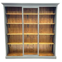 Painted pine open bookcase, projecting cornice and panelled sides, four fixed shelves, raised on platform 