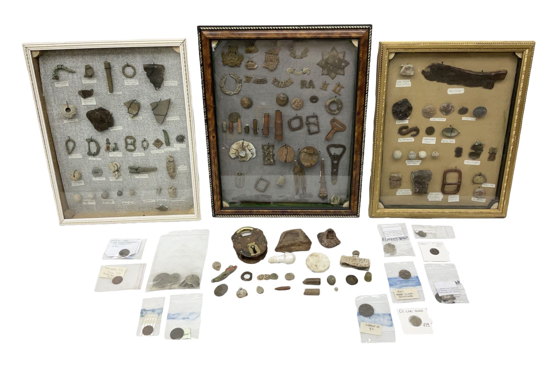 Collection of metal detecting finds, most contained within display frames and labelled, some loose, to include musket balls, bill hook, axe fragment, hubcaps, shell cases, regimental badges, coins, etc. 