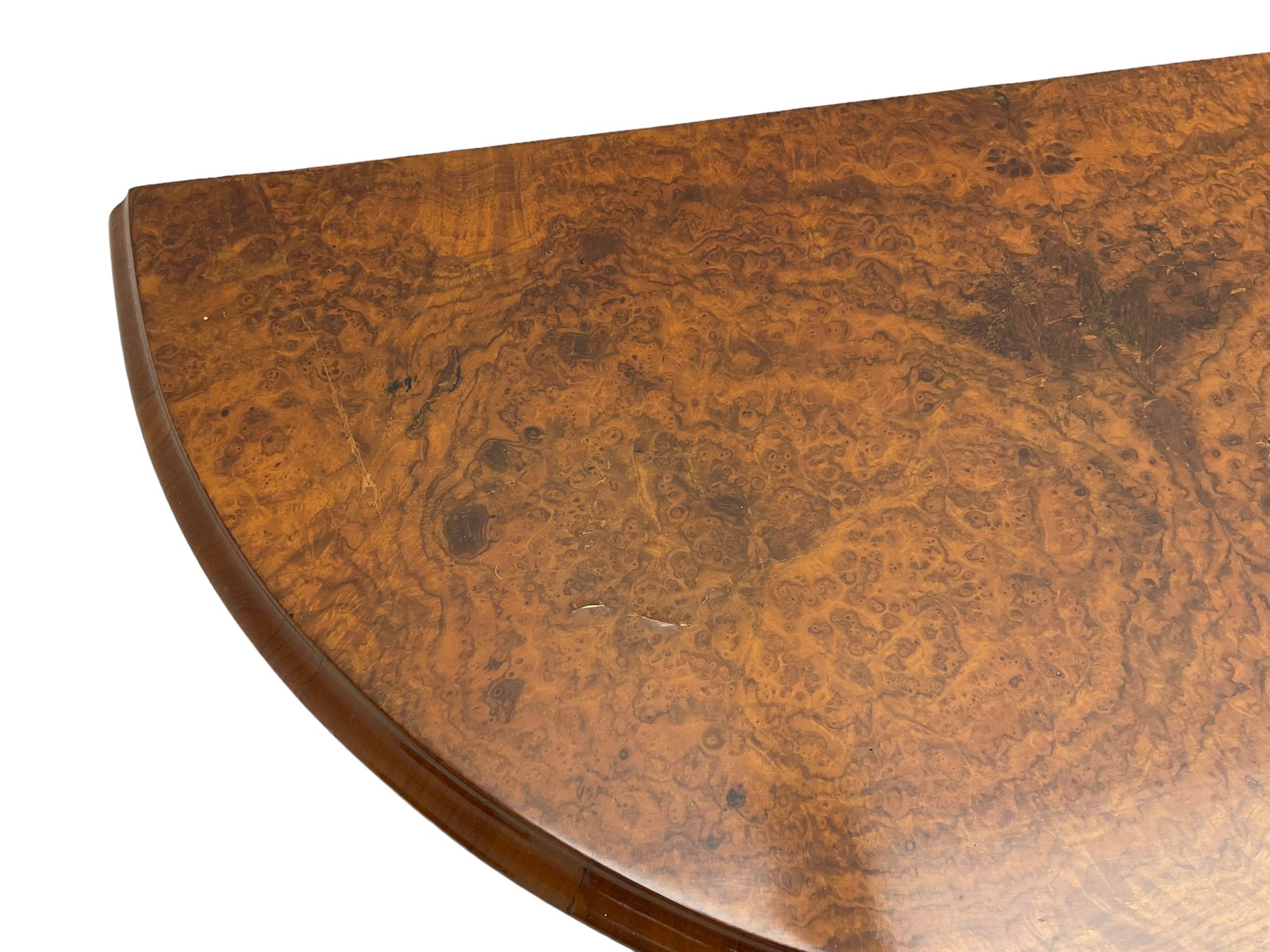 Victorian figured walnut demi-dune card table, the fold-over moulded top with circular baize lining, on four turned pillars with central finial platform, four splayed moulded supports with angular scrolled feet, on castors