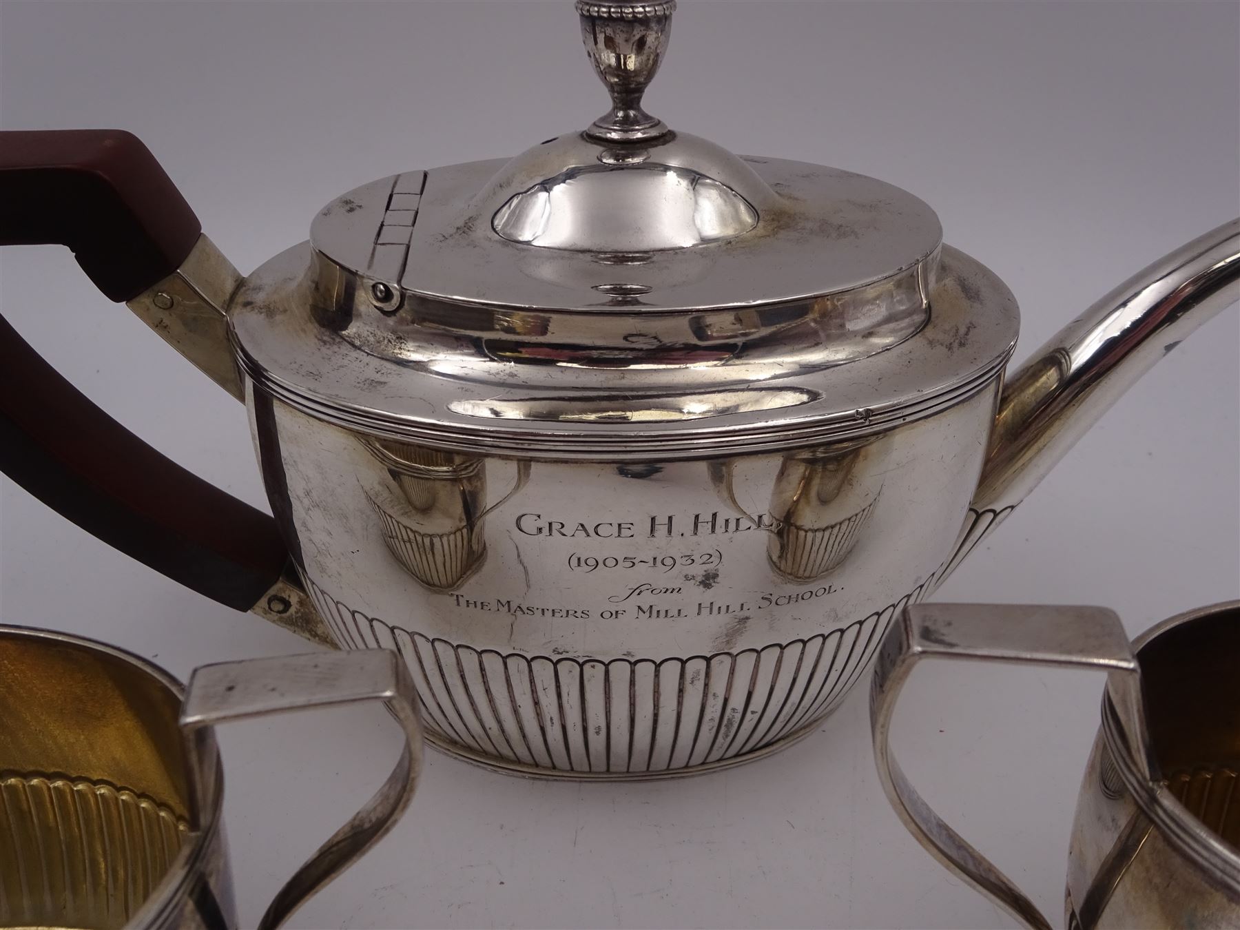 1930s American silver three piece batchelors tea service, comprising teapot, twin handled open sucrier and milk jug, each of part fluted oval form, the teapot with personal engraving to body, wood effect handle and silver urn shaped finial, stamped sterling with maker's mark for Gorham, teapot H13cm