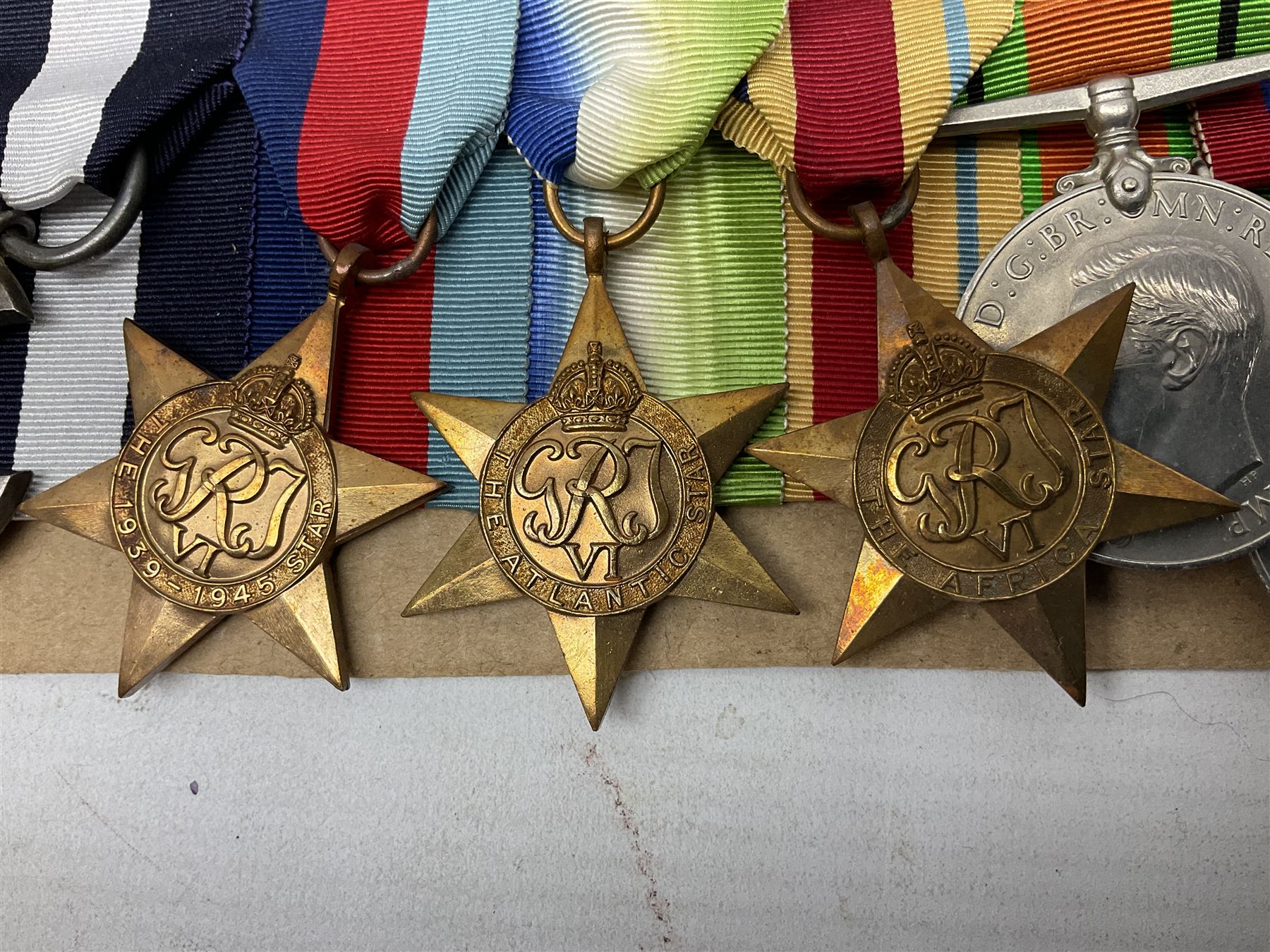 WW2 Royal Naval group of eight medals comprising OBE, hallmarked silver Distinguished Service Cross inscribed verso Lieut. J.R. McCluskie RNVR 1945, 1939-1945 Star, Atlantic Star, Africa Star, 1939-1945 War Medal, Defence Medal and Royal Naval Patrol Service Medal inscribed Lieutenant J.R. McCluskie Royal Naval Patrol Service; with seven original photographs of a sea battle 27th November 1940 against the Italian Fleet and another photographic postcard of Sir Stafford Cripps arriving on board one of the vessels.