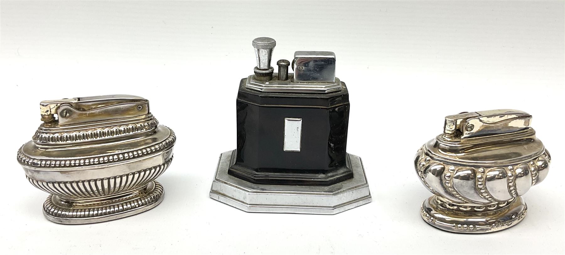 A Ronson Touch Tip chrome and bakelite table lighter, together with two silver plated Ronson table lighters. 