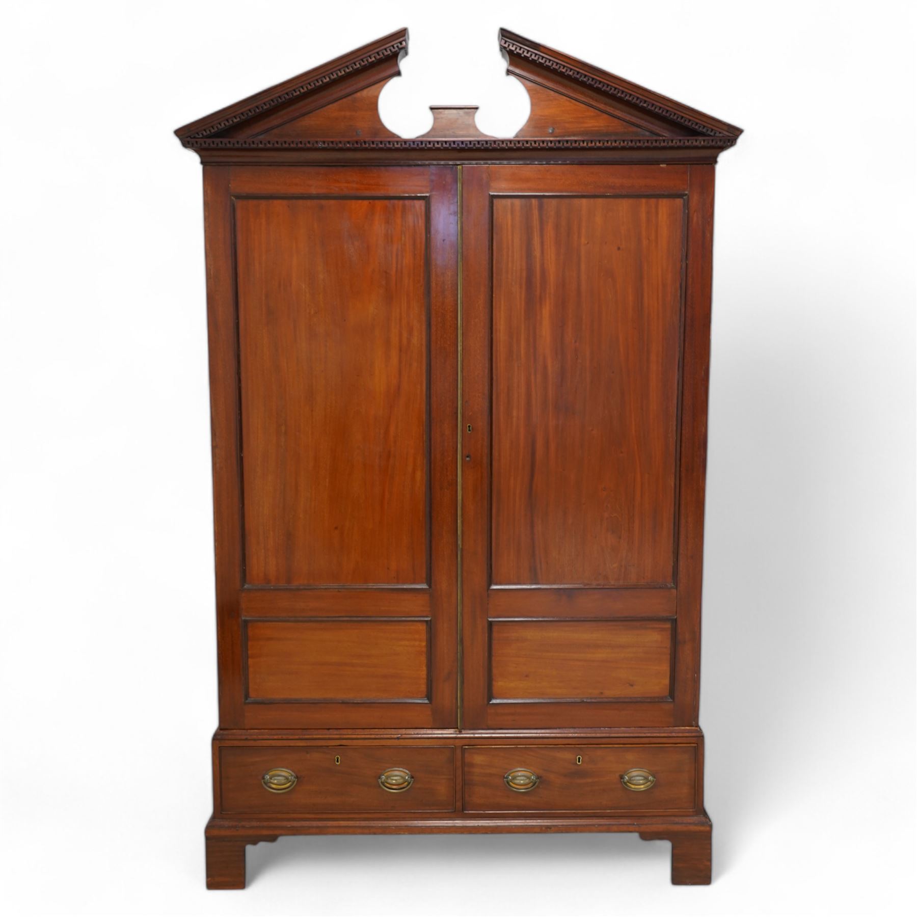 George III mahogany wardrobe, broken sloped arch pediment with dentil moulding over two panelled doors, the base fitted with two cock-beaded drawers, on bracket feet, knock-down construction 