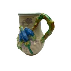 Clarice Cliff baluster jug moulded with a blue budgerigar perched upon branch with green rustic handle and mushroom glaze,  factory stamped beneath, H22.5cm