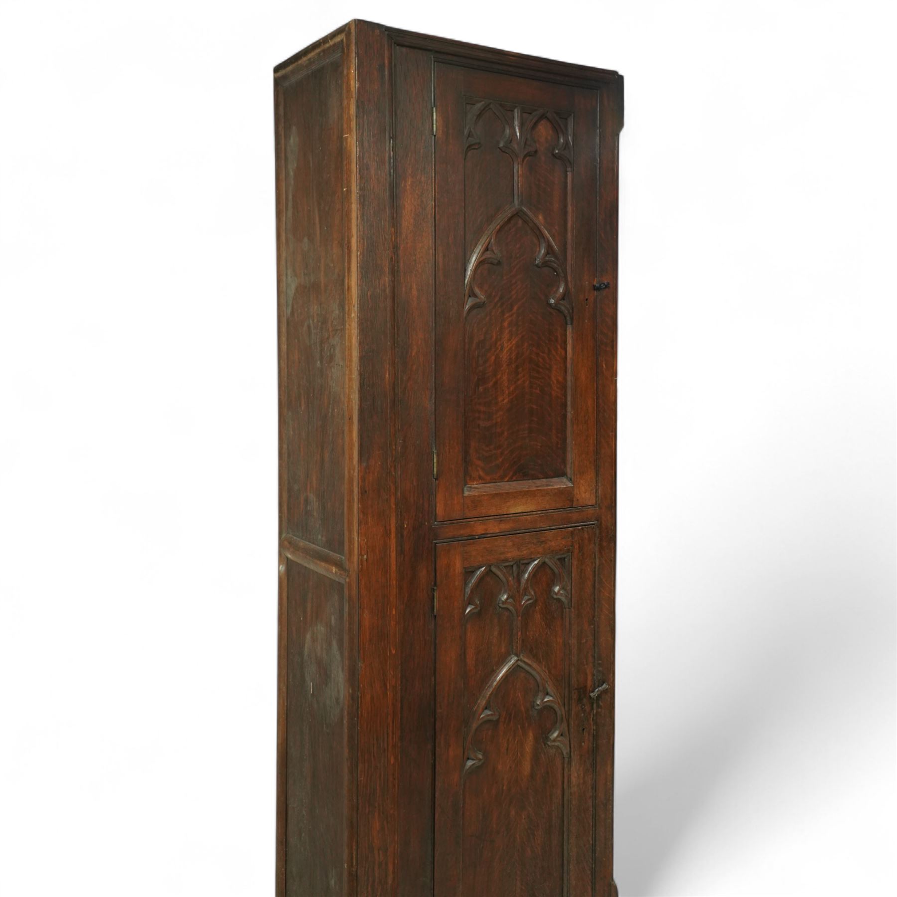 19th century Gothic Revival oak Sacristy vestment cupboard of tall proportions, fitted with two ecclesiastical trefoil moulded panelled doors enclosing four shelves, flanked by a chamfered corner, the side panelled and moulded with matching sacristic architectural mouldings, on skirted base
