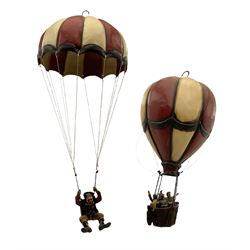Painted wooden hanging model of a hot air balloon group, the balloon above a wicker basket complete with sandbags and figures, together with a similar example with a clown figure below, H68cm