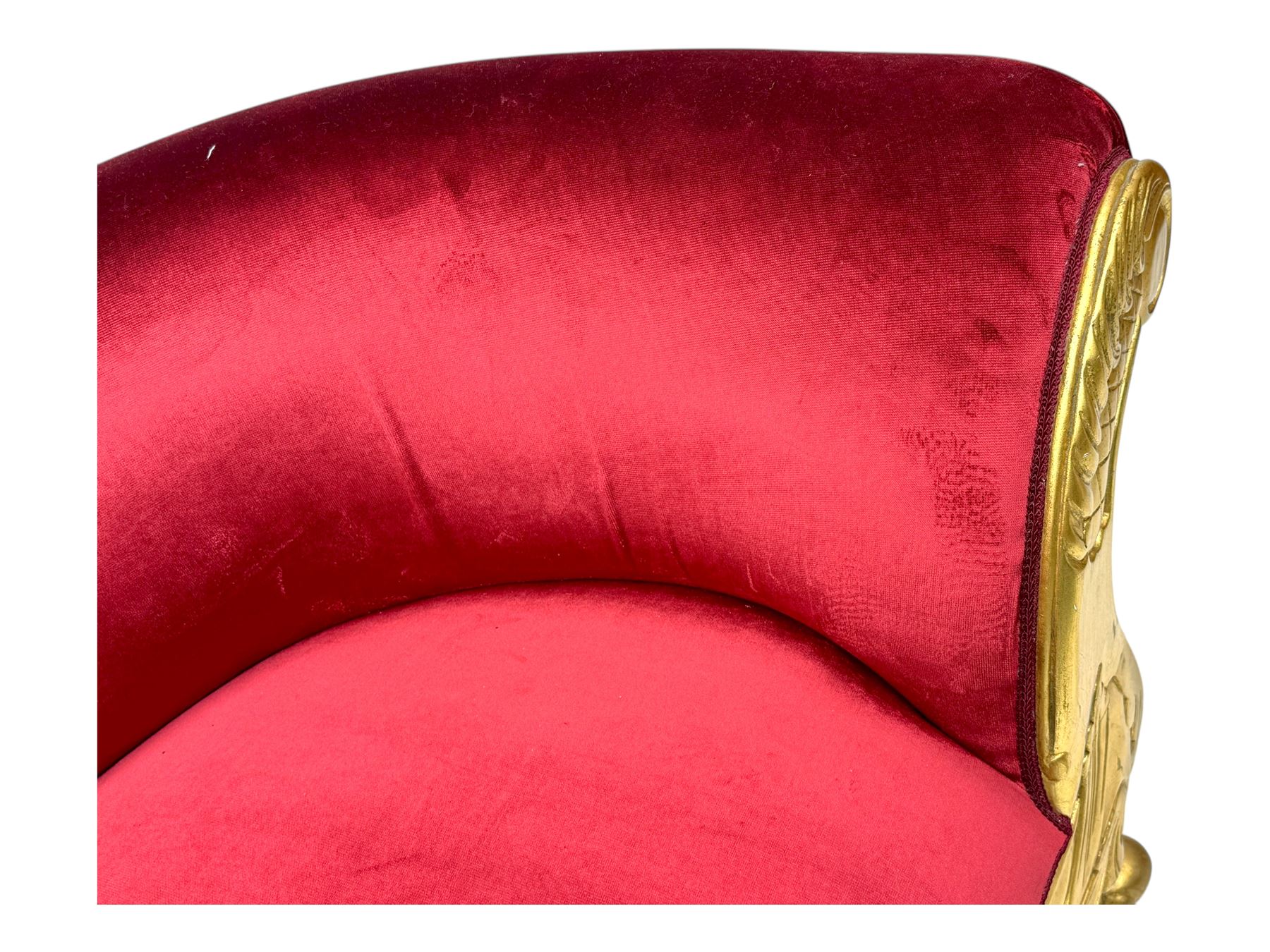Victorian design giltwood chaise longue, the curved backrest and seat upholstered in deep red velvet with tufted detailing, the frame carved with floral motifs and scrolling acanthus leaves, raised on shaped cabriole supports