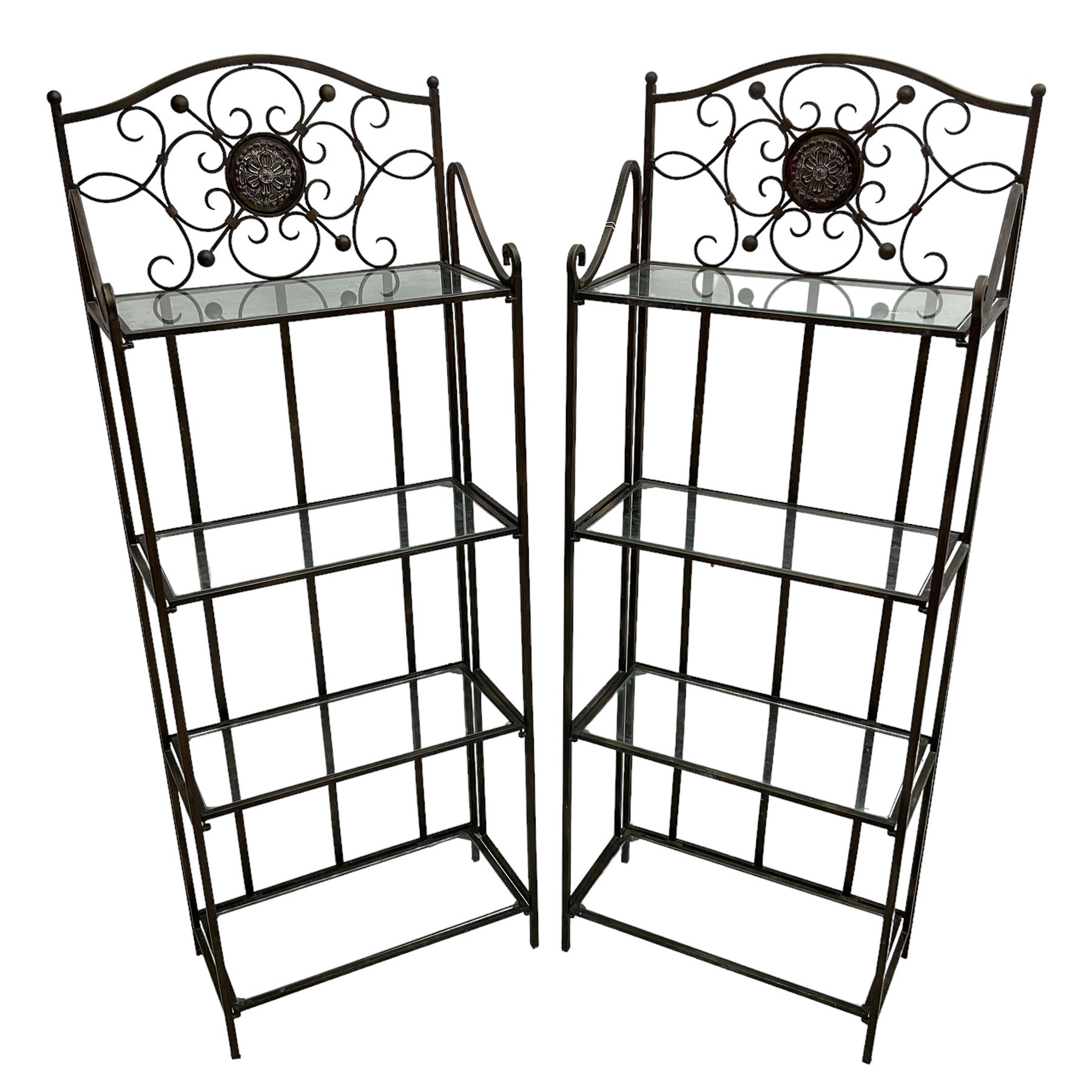 Pair of wrought metal conservatory plant stands, raised back with scrolling design, each fitted with three glass shelves