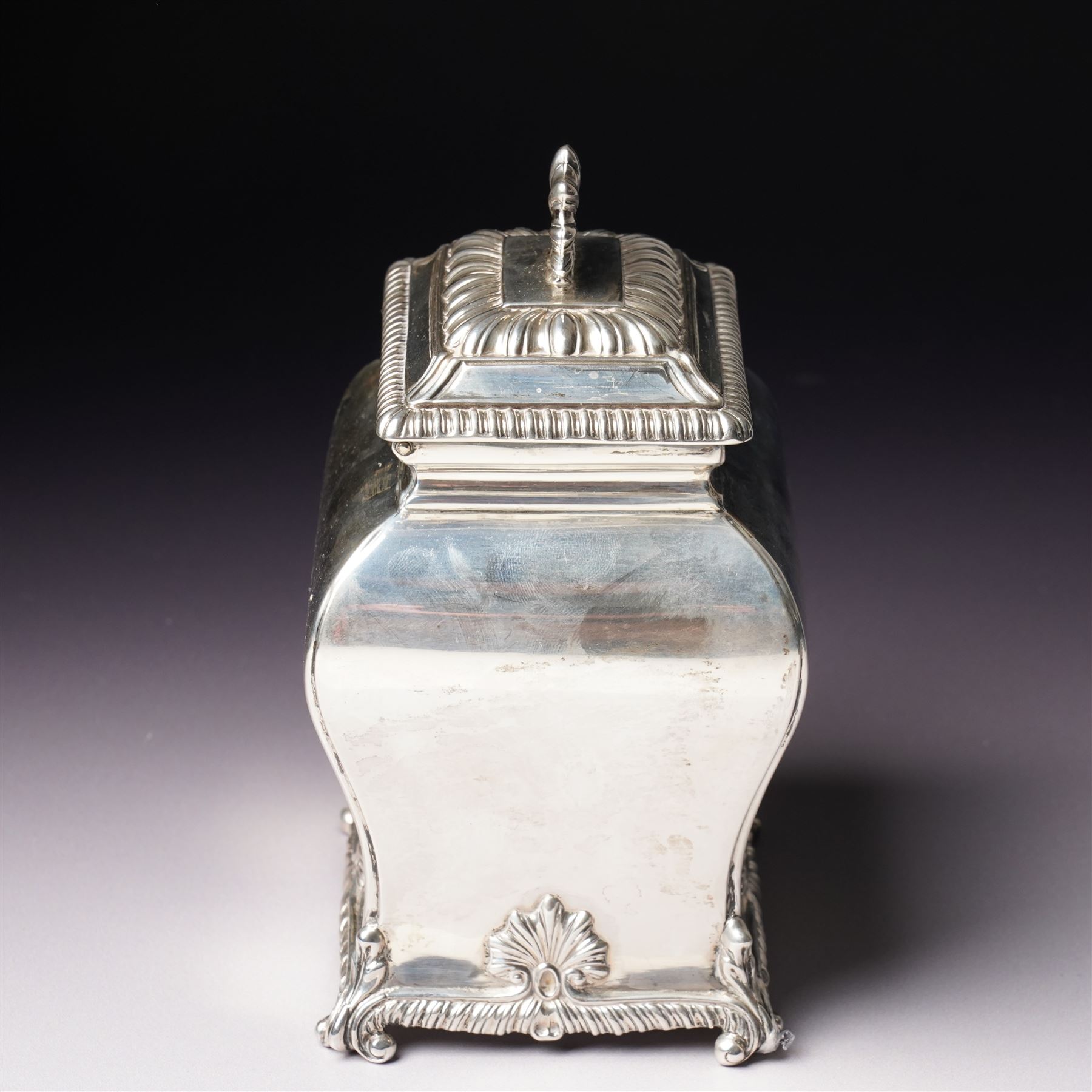 Edwardian silver tea caddy of bombe outline with shell moulded finial, shell moulded and gadrooned base on scroll feet H15cm London 1902 Maker Thomas Bradbury & Sons
