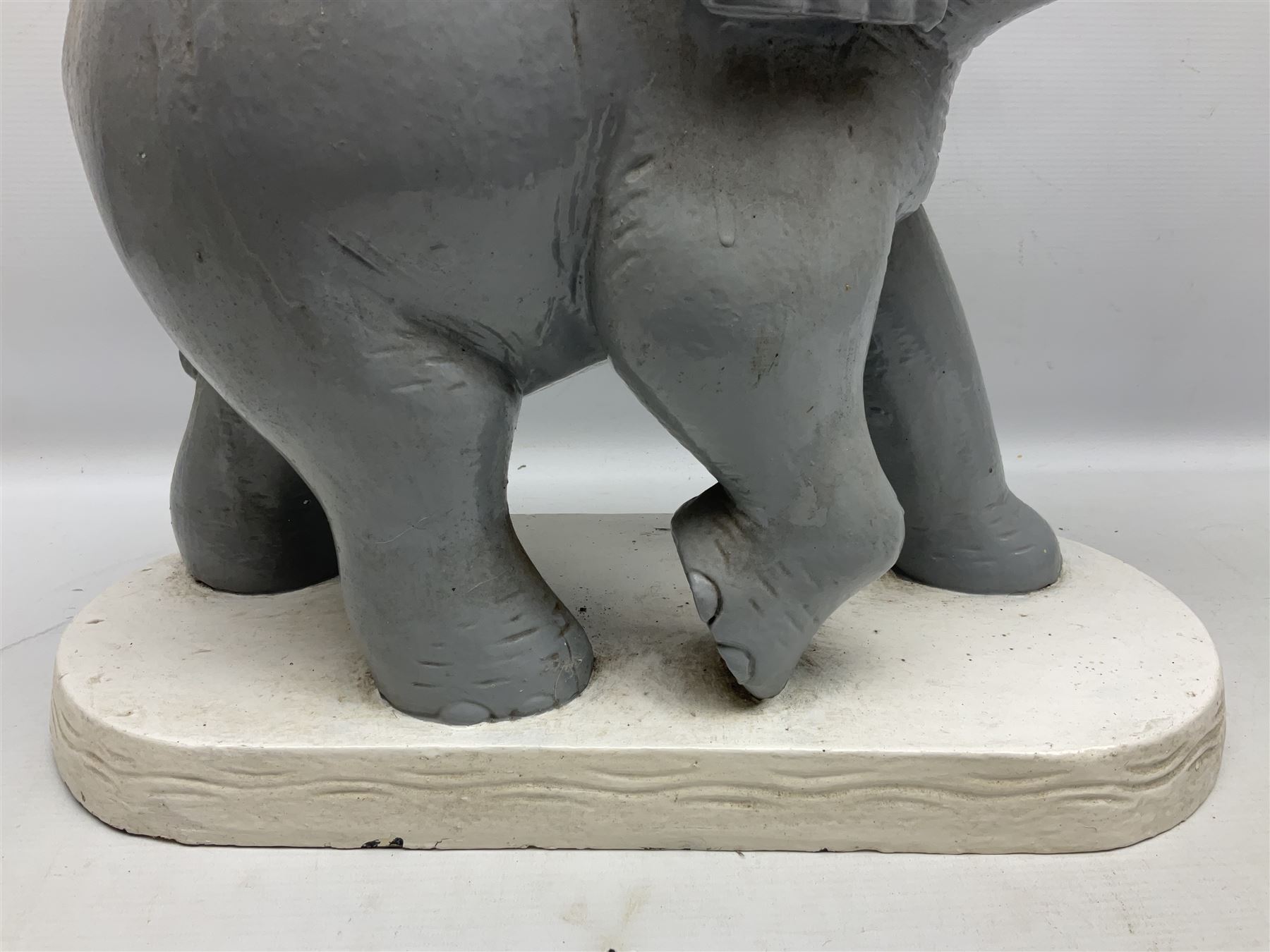 Composite figure of an elephant, painted grey, upon white base, L45cm H65cm