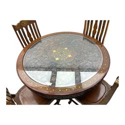 Pakistan carved hardwood brass inlaid circular dining table, and four rail back chairs with saddle seats
