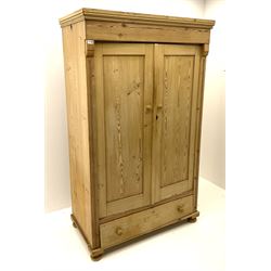 Continental pine wardrobe fitted with two panelled doors enclosing fitted interior, above long drawer, raised on bun feet 